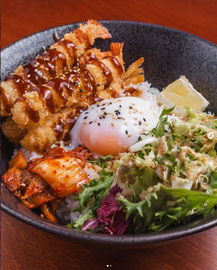 Cuenco de arroz con pollo frito, huevo poché, kimchi y ensalada