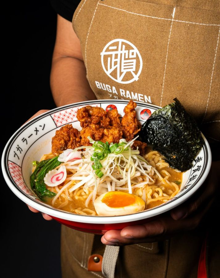 Cuenco de ramen con pollo frito, huevo, naruto y alga nori, servido en mano